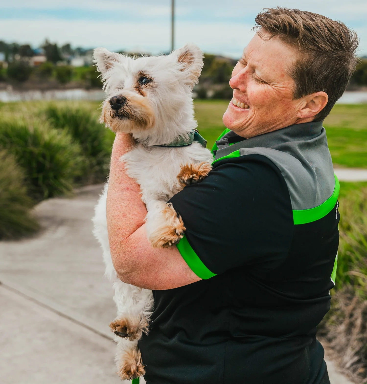 A freshly groomed dog held by the Pawsome team